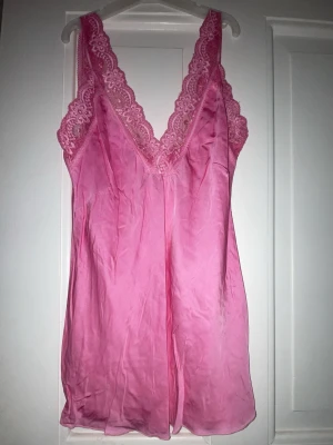 Rosa linne med spetsdetaljer - Sött rosa linne i mjukt, glansigt material med breda axelband och v-ringning dekorerad med spets. Lätt och luftigt tyg som ger en bekväm känsla. Perfekt för sommaren💕💕