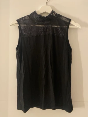 Svart topp från Alice Bizous - Snygg svart ärmlös topp från Alice Bizous med hög hals och vacker spetsdetalj upptill. Inte använd och pris kan diskuteras skriv om ni är intresserade.