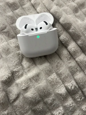 Apple AirPods Pro med laddningsetui - Säljer ett par vita Apple AirPods Pro med trådlöst laddningsetui. Hörlurarna har en stilren och kompakt design i blank plast och passar perfekt för dig som vill ha grymt ljud och smidig anslutning till din iPhone eller andra Apple-enheter. AirPods 4