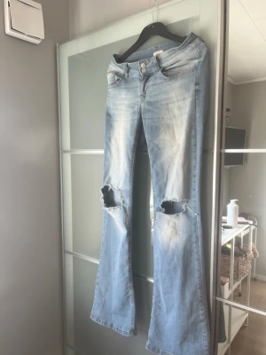 Ljusblå bootcut jeans med hål - Skit snygga jeans från Nelly med håll,st 36,använda men fortfarande fint skick!!!