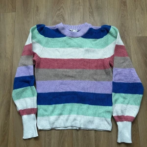 Randig stickad tröja i flera färger - Färgglad randig stickad tröja från Cubus. Ärmarna är något puffiga. Sparsamt använd, dock lite nopprig!