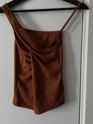 Brun ribbad linnetopp från SHEIN - Snygg brun ribbad linnetopp från SHEIN med smala axelband och draperad front. Perfekt att styla med jeans eller kjol för en trendig look. Banden knyts i kors över bröstet