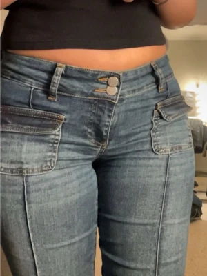 Nelly bootcut jeans med ränder  - Säljer dessa trendiga Nelly Jeans i bootcut vintage modell. De har en  blå ”washed” vintage färg med låg midja och dekorativa sömmar som bildar ränder framtill. Jeansen har fickor samt dubbel knapp framtill. Materialet är jeans men ändå super stretch material så formas efter kroppen. Framhäver formerna med en figurnära passform som passar flera storlekar tack vare stretchen. Först till kvarn, säljer billigt då jag ska flytta och storrensar. Säljs inte längre på Nellys hemsida.  