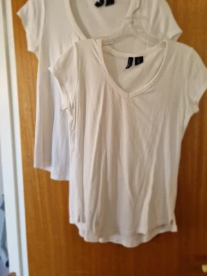 Vita basic t-shirts med v-ringning från Cynthia Rowley - Två vita basic t-shirts från Cynthia Rowley med v-ringad hals och små sprund i sidorna. Perfekta till jeans eller shorts. 48% bomull, 48% modal och 4% spandex. Inga fläckar, har legat nerpackade men blir fina efter ett drag med strykjärnet. Priset är för båda.