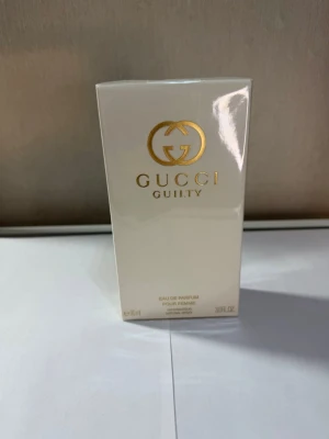 Gucci Guilty Eau de Parfum 90ml - Gucci Guilty Eau de Parfum Pour Femme i en elegant, ljusbeige kartong med guldiga detaljer. Lyxig och modern doft från Gucci, perfekt för dig som vill sticka ut. Flaskan rymmer 90 ml och förpackningen har en exklusiv känsla med stilren design.
