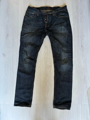 Mörkblå jeans från Nudie - Snygga mörkblå jeans från Nudie. Jeansen är i modellen grim tim I storleken W 32 L 32.. Tillverkade i slitstarkt denimtyg. Vid minsta fundering hör av dig 🙌