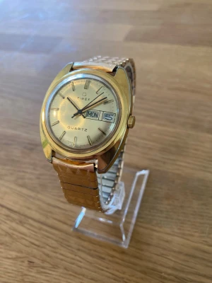 1978 Timex Q DayDate Gold 37mm Herrur - Säljer en riktigt snygg guldpläterad vintage herrklocka från Timex i nyskick enligt bilder. Fungerar bra, armband i flexband stål, dag och datumvisare, rejält mineralglas, japanskt urverk, vattentät, osv. Behöver bara nytt batteri.  Nypris: 2000-3000+ SEK Mitt pris: 889 SEK  Skickas snabbt och spårbart. Skriv vid frågor och se gärna mina andra annonser!