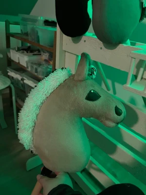 Ljusbrun käpphäst med fluffig man - Säljer en ljusbrun käpphäst med mjuk plysch och vit, fluffig man med svart rand längs mitten. Hästen har broderade detaljer på ögon och nos samt två små öron. Perfekt för lek och fantasi!