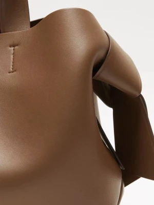 Brun handväska från Acne Studios - Cool brun handväska i slätt läder från Acne Studios med unika knutdetaljer på sidorna och diskret logga framtill. Väskan har en mjuk, skulptural form och korta handtag som gör den enkel att bära. Perfekt för dig som gillar stilren och modern design.