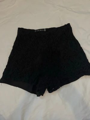 Svarta spets-shorts från new yorker  - Säljer ett par svarta högmidjade shorts från new yorker med snygg spetsdetalj. De har en elegant och med ett inner tyg i shortsen.