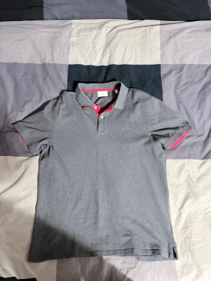 Gant Piké - Piké ifrån Gant i grå färg med röda detaljer. Stilig och i mycket fint skick.   Storlek: L