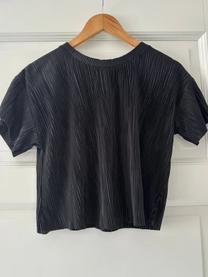 Svart  topp från Bershka - Snygg svart topp från Bershka med korta ärmar. Perfekt för en utekväll. Kan stylas med höga jeans eller kjol för en trendig look.