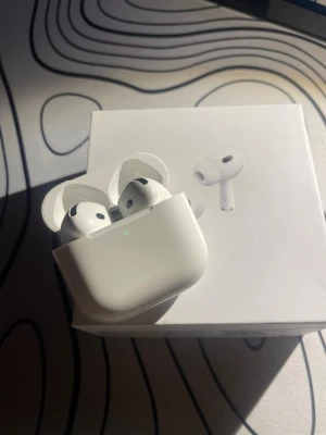 Apple AirPods Pro 4  - Säljer ett par vita Apple AirPods Pro med aktiv brusreducering och trådlöst laddningsetui. Hörlurarna har en stilren och kompakt design i plast och levereras i originalförpackning med tillhörande manualer. Perfekta för musik, samtal och gaming.