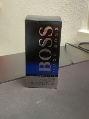 Hugo Boss Bottled Night 100ml EdT - Hugo Boss Bottled Night Eau de Toilette 100ml med en elegant mörkblå glasflaska och matchande förpackning. Flaskan har en stilren, cylindrisk form med präglad logga. Doften är maskulin och modern, perfekt för kvällsbruk.