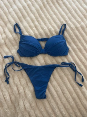 Blå bikini från Calzedonia - Snygg blå bikini från Calzedonia med vadderad bygel-bh och knyt i sidorna på underdelen. Superfin rosettformar överdel. Säljer pga blivit för liten. 💙