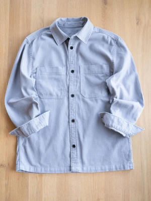 Ljusgrå overshirt med fickor, size M - Snygg ljusgrå overshirt med två stora bröstfickor och svarta knappar. Skjortan har klassisk krage och långa ärmar. Perfekt att bära öppen eller stängd för en avslappnad stil.