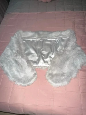 Ljusgrå fuskpäls-sjal - Mjuk och fluffig ljusgrå sjal i fuskpäls med slät, glansig insida. Perfekt för att ge din outfit en lyxig touch och hålla dig varm under kyliga dagar. Snygg att slänga över axlarna för en trendig look.