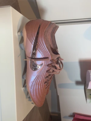Nike Tiempo  - Snygga fotbollsskor från Nike i metallic-rosa färg med silvrig swoosh på sidan o skruvdobbar. Använda några gånger så de är enbart lite smutsiga på tyget upptill, låda och påse följer med.