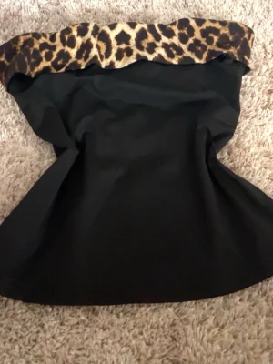 Svart tubtopp med leopardmönster😍 - As snygg svart tubtopp med leopardmönstrad kant upptill. 💓Perfekt för sommarkvällar, kanske lite mer festlig 🥂🍸. Toppen är axelbandslös och har en tight passform som framhäver figuren. Storlek passar för dig som är XS/S. Säljer då jag jag för mycket kläder och den tyvärr inte kommer till användning längre. Har du frågor så får du gärna skriva i dm !🥰