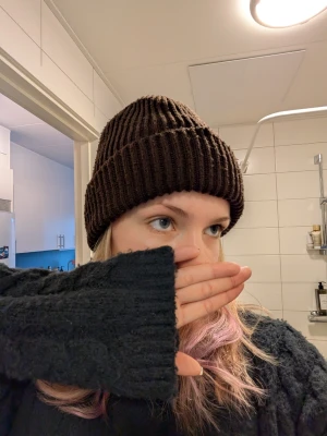 Mörkbrun ribbstickad mössa - Säljer en mörkbrun ribbstickad mössa med klassisk uppvikt kant. Mössan är i mjukt och stretchigt material som sitter skönt på huvudet. Perfekt för kalla dagar och enkel att matcha med olika outfits.