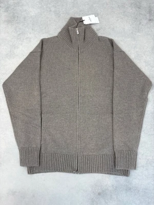 Beige stickad ziptröja Gran Sasso - Snygg beige stickad tröja från Gran Sasso med dragkedja framtill och hög ribbad krage. Tröjan har ribbade muddar vid ärmslut och nederkant, perfekt för lager på lager. Tillverkad i mjukt material som känns lyxigt och bekvämt.