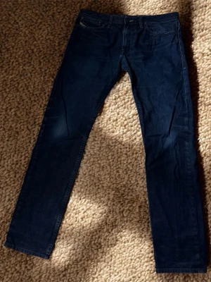 Mörkblå slim jeans från Diesel - Säljer ett par mörkblå slim-skinny jeans från Diesel, modell Shioner. Klassisk design och raka ben. Midjan är 42cm bredd och längden är 99cm. Skriv gärna vid frågor. Priset kan diskuteras.