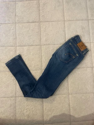 Blå jeans från Dondup - Snygga blå jeans från Dondup med klassisk femficksdesign och kontrastsömmar. Jeansen har en skinnpatch med logga bak i midjan och raka ben. Perfekta till en avslappnad stil och tillverkade i mjukt denimtyg.