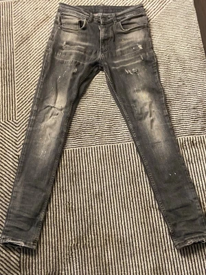 Grå slitna skinny jeans - Säljer ett par grå skinny jeans med slitningar och distressed detaljer på framsidan. Jeansen har fem fickor, dragkedjegylf och är tillverkade i denim med stretch. Perfekta för en avslappnad och trendig look. Passar alla som är ungefär 145 till 155 om du vill att den ska vara lite baggy 