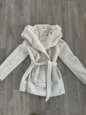 teddy kappa beige 34 - lite längre tjock ljus beige teddy kappa som man kan knyta i midjan, använd en del men fortfarande bra skick. stl 34💞 kan nog passa en S också!