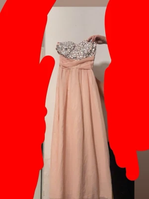 Lång ljusrosa klänning med stenar - Elegant långklänning i ljusrosa med glittriga stenar och pärlor upptill. Axelbandslös modell med svepande kjol i tunt tyg och markerad midja. Perfekt för bal eller festliga tillfällen. Skulle haft den på min bal men hitta en annan priset kan diskuteras speciellt vid snabb affär 