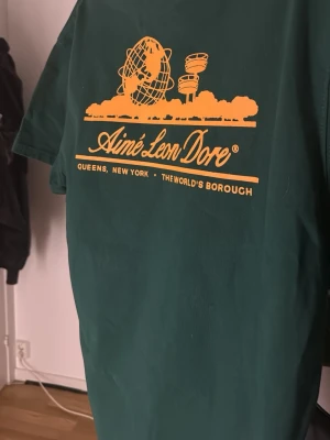 Grön Aimé Leon Dore t-shirt - Mörkgrön t-shirt från Aimé Leon Dore med gult tryckt. Tjock o skön t shirt som är oversized i stl S, eftersom den är oversized så har den aningen kortare ärmar men i övrigt väldig snygg