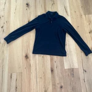 Mörkblå långärmad piké Zanone - Snygg mörkblå långärmad pikétröja från Zanone med klassisk krage och knäppning framtill. Tillverkad i mjukt och stretchigt material som ger en clean och stilren look. Perfekt för dig som gillar minimalistisk stil. Passar M/S.