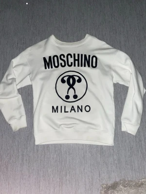 Vit sweatshirt - Säljer en vit sweatshirt med stor svart logga och texten 'Milano' på framsidan. Tröjan har rund halsringning, långa ärmar och är gjord i mjukt material. Hör av er vid funderingar! Jag skulle säga att den sitter som S-M 