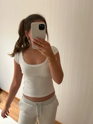 Vit ribbad topp Zara - Säljer en vit topp från Zara med urringning och korta ärmar. Toppen är ribbad och passar till många outfits!