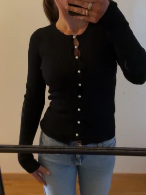 Svart ribbad kofta med pärlknappar - Superfin tröja med pärlknappar från Ginatricot aldrig använd, prislapp kvar. 