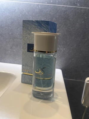Kaaf Extrait de Parfum  100ml - Fräsch Eau de Parfum från Kaaf i en elegant glasflaska med blått innehåll och gulddetaljer. Flaskan har en stilren vit kork och kommer i en matchande blå kartong med gulddetaljer och arabiska bokstäver. Perfekt för dig som gillar exklusiva dofter.
