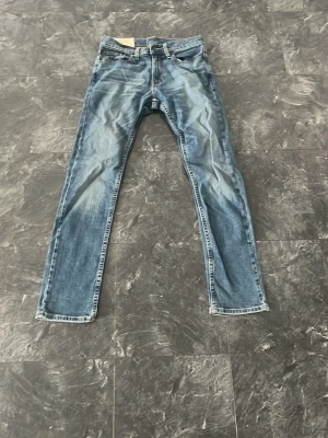 Blå raka jeans från Hollister - Säljer ett par klass assistent blå skinny jeans från Hollister med Co ol slitningar. Jeansen@ har fem fickor och klassisk gylf med dragkedja och knapp. sopassade för dig som gillar en avslappnad stil. Materialet är bomull. Storleken är 28/30
