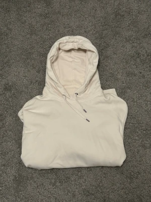 Vit hoodie från Uniqlo - Clean vit hoodie från Uniqlo med huva. Tillverkad i mjukt bomullsmaterial som känns skönt mot huden. Perfekt för en avslappnad och stilren look. Diskret design utan tryck eller logga på framsidan.