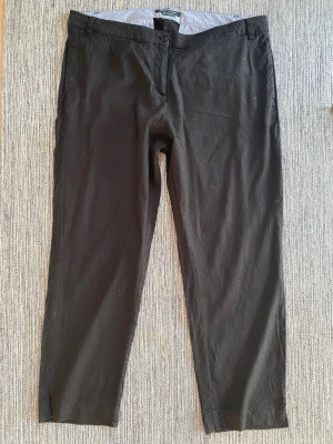 Svarta chinos med slits vid benslut - Marc O’Polo chinos för dam i svart färg, storlek 44. Byxorna är tillverkade i linne och har klassisk chinosmodell med knapp- och dragkedjegylf. Modellen har fickor fram och bak samt små slitsar vid bensluten. Passar som vardags- eller kontorsbyxa.  Sparsamt använda och i fint begagnat skick   Mått Över midjan: ca 50,5 cm Längd från grenen och ner: ca 68 cm  58% linne, 39% viskos och 3% elastan  Kommer från ett djur och rökfritt hem 