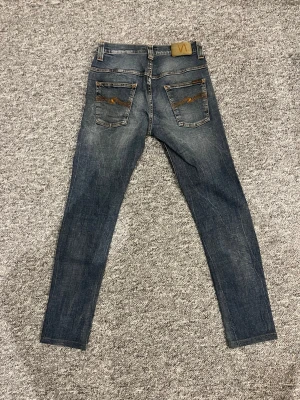 Nudie jeans  - Säljer ett par blå Nudie jeans med riktigt schyssta fades och som är helt perfekta till våren