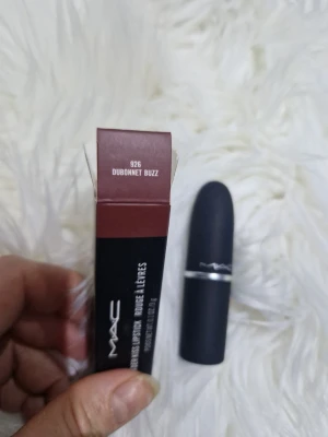 MAC Powder Kiss Dubonnet Buzz läppstift - MAC Powder Kiss Lipstick i nyansen 926 Dubonnet Buzz. Färgen är en djup rödbrun ton med matt finish. Hylsan är svart med en silvrig detalj och har den klassiska MAC-formen. Perfekt för dig som vill ha en mjuk, suddad look på läpparna.