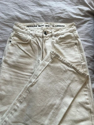 Vida vita jeans regular waist - Säljer ett par snygga vita jeans med regular waist och raka, vida ben. 