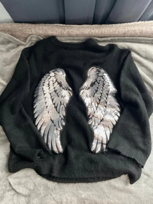Svart stickad tröja med wings  - Cool svart stickad tröja med stora silvriga paljettvingar på ryggen🪽Storlek:XS,S!!