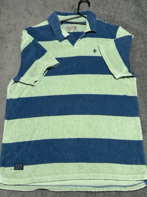 Morris Stockholm Terry Polo – Striped – Size M - Stilren piké från Morris Stockholm i mjukt terry-material med gröna och blå ränder.  Perfekt som sommarplagg eller för en avslappnad preppy look.  Detaljer • Morris Stockholm • Terry / handduksmaterial • Randig (grön/blå) • Storlek M  📦 Snabb frakt 💬 Hör av dig vid frågor