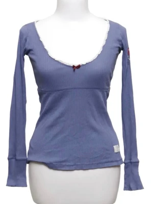 Ljusblå ribbad topp med spets - Ljusblå långärmad topp med ribbad struktur och djup v-ringning dekorerad med vit spetskant och en liten rosett framtill.  Bra skick!! Från Odd-Molly. Kan posta snabbt. Passar också S.