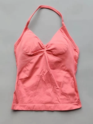 Rosa halterneck linnetopp - Snygg rosa linnetopp med halterneck och lätt rynkning vid bysten. Toppen är ärmlös och har en feminin passform. Tillverkad i mjukt bomullsmaterial. Passar som S🥰