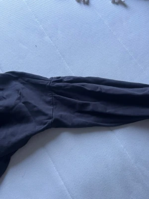 Svart topp från I dig denim - Snygg svart topp från I dig denim med långa ärmar och enkel, stilren design. Tillverkad i mjukt och stretchigt material som sitter skönt på kroppen. Perfekt att matcha med jeans eller kjol för en clean look.