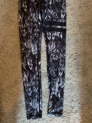 Svarta leggings med fjädermönster Stronger - fint använt skick, inga hål eller fläckar. * Märke: Stronger * Storlek: S * Färg: Svart/vit Pris kan diskuteras!