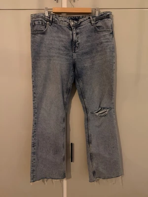 Ljusblå raka jeans med slitning - Ljusblå jeans med rak passform. Jeansen har en tydlig slitning på höger knä och klassisk femficksdesign. Är avklippta så de passar någon som är 1,57cm. Ljuset på första bilden ser ut som de har en smutsig fläck men de stämmer ej, blev något konstigt med fotot.😅