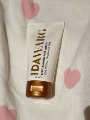 Ida Warg brun utan sol ansiktskräm - Self-tanning face lotion från Ida Warg, 50 ml. 100% vegansk och parfymfri brun utan sol-kräm för ansiktet. Kommer i en vit tub med guldigt lock och text i guld. Perfekt för en solkysst look året runt.